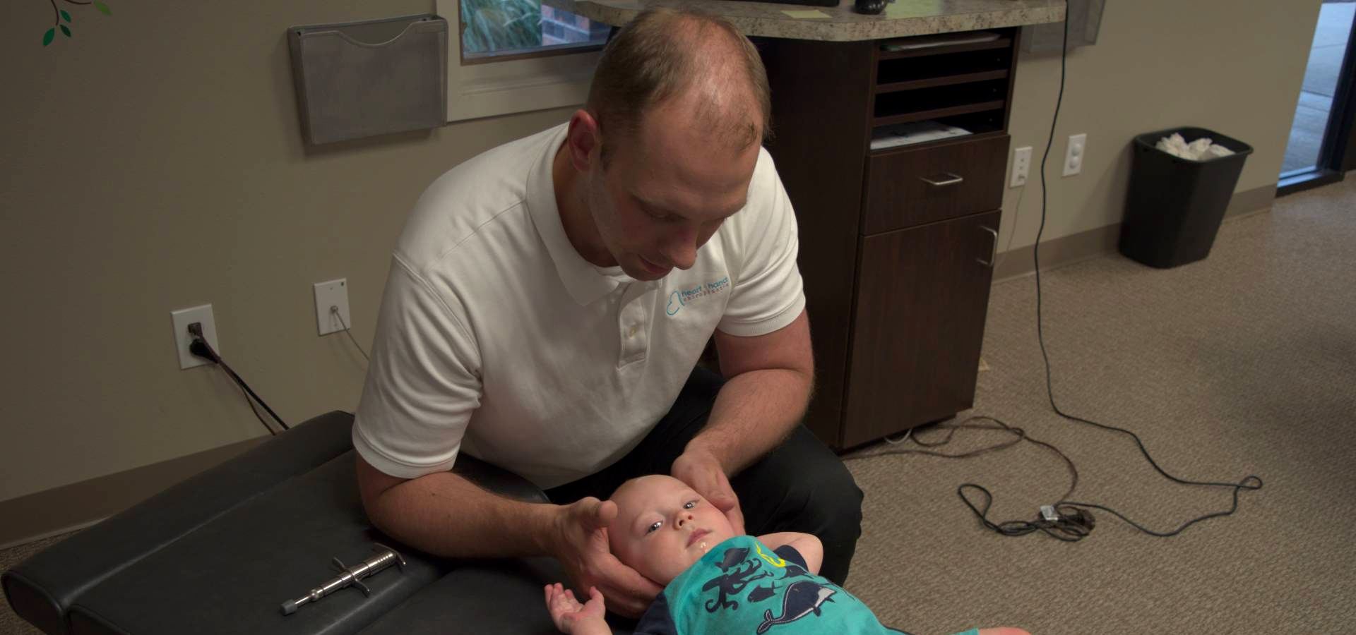 Heart & Hand chiropractor gently adjusting an infant on the treatment table